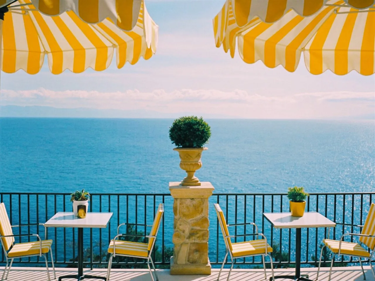 Cira 200 film stock in Chromogen, an easy consumer negative scan: a seaside terrace under yellow striped umbrellas