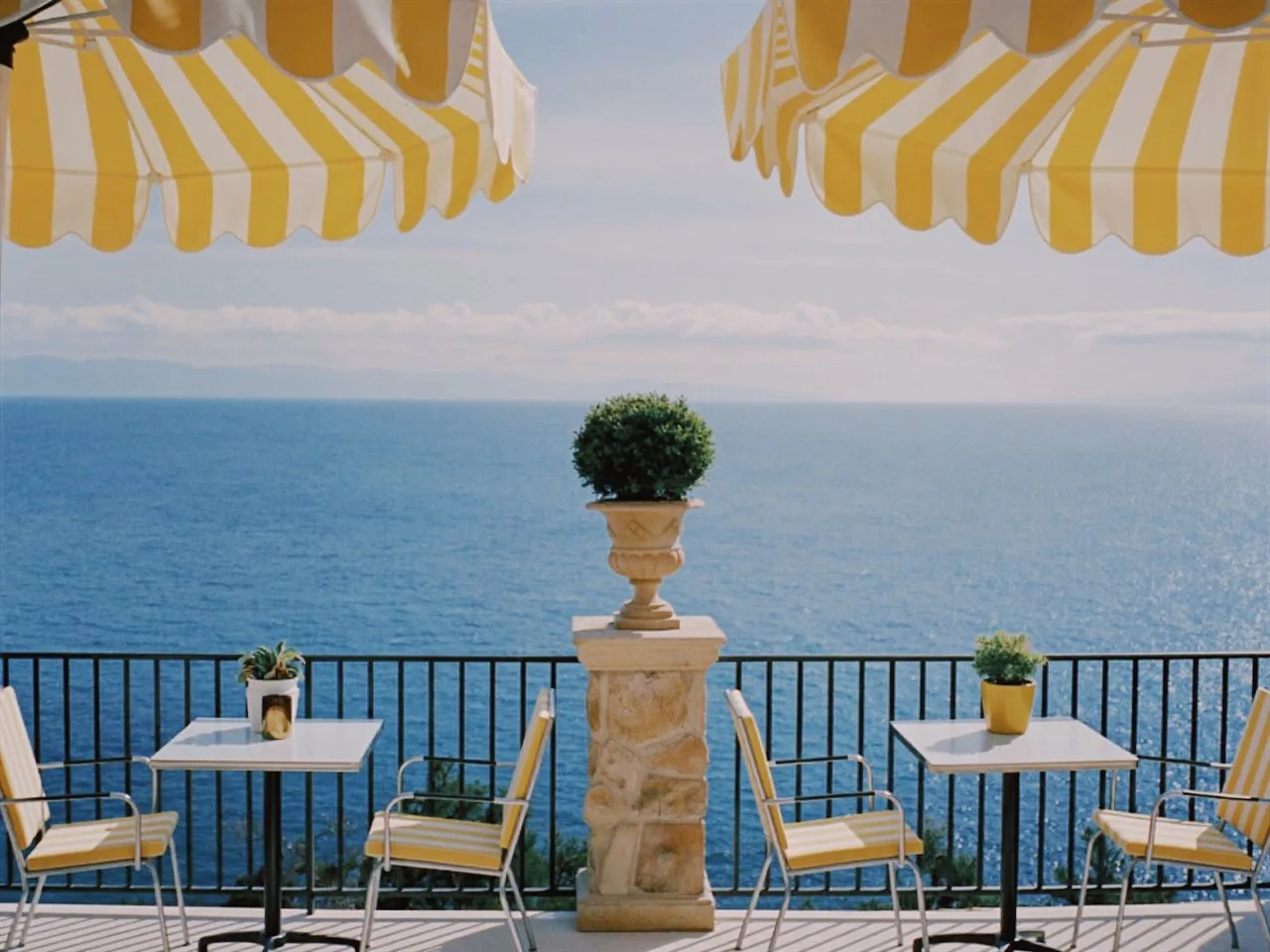 Prisma film stock in Chromogen, a crisp digital slide look: a seaside terrace under yellow striped umbrellas