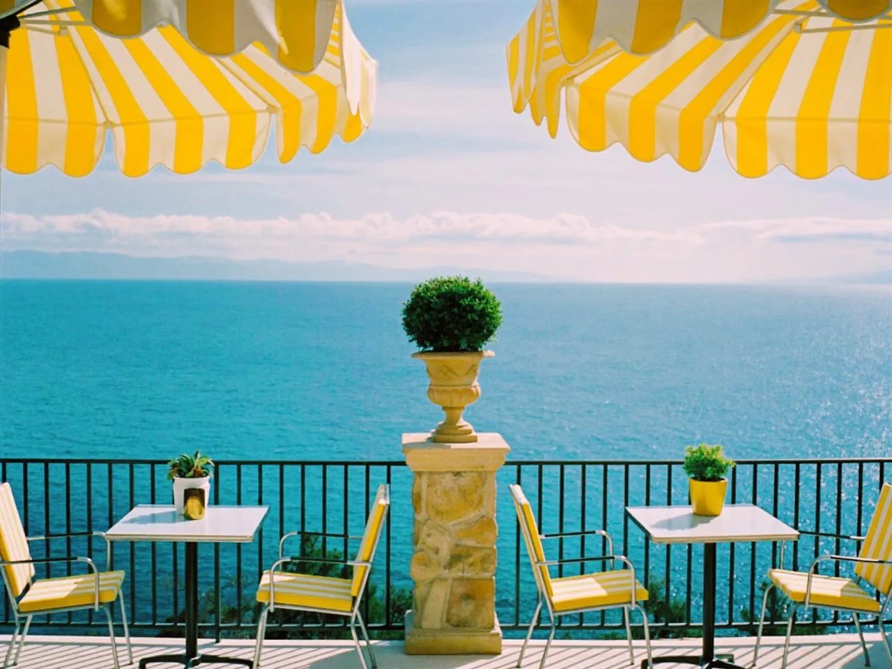 Verel 400 film stock in Chromogen, a soft pastel negative: a seaside terrace under yellow striped umbrellas