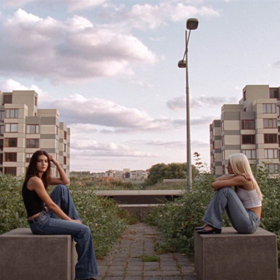 Library photo: two friends sitting on concrete blocks between apartment buildings