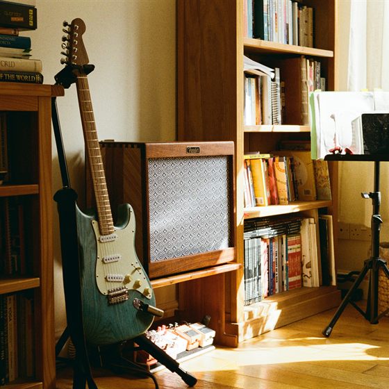 Library photo: an electric guitar beside a wall of bookshelves