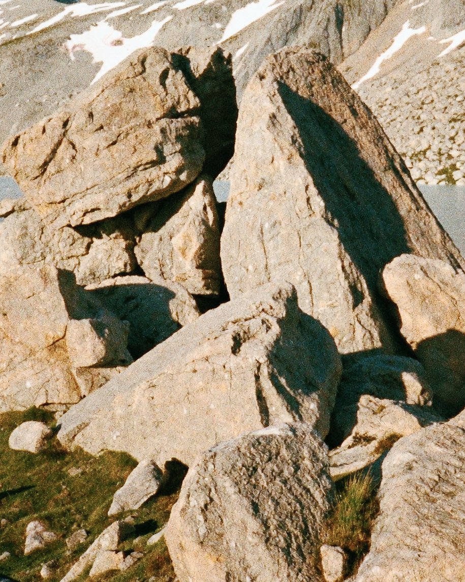 A film-rendered photo of sunlit granite boulders, their gritty stone texture and hard edges rendered with film sharpness
